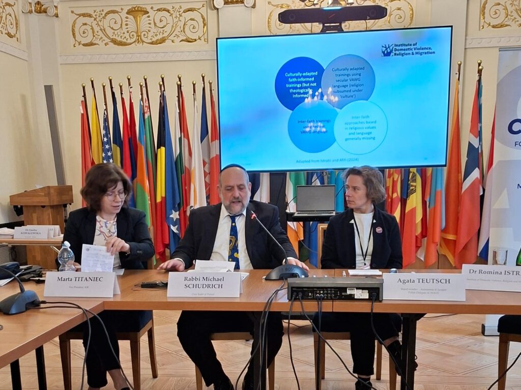 zdjęcie przedstawia rabina i dwie kobiety siedzących przy stole i okmawiających zagadnienie